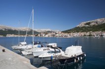 Barca ormeggiata nel porto dell'isola di Krk con la città Baska sullo sfondo, Croazia — Foto stock
