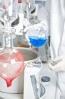 Joven científico masculino examinando líquido azul en evaporador rotatorio en laboratorio - foto de stock