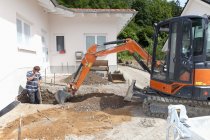 Operaio che scava terreno con escavatore in cantiere — Foto stock