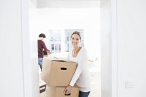 Femme déchargeant des boîtes dans une nouvelle maison avec l'homme sur fond — Photo de stock