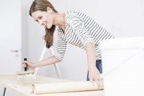 Frau trägt Kleber auf Tapete auf — Stockfoto