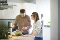 Glückliches Paar bereitet gemeinsam Salat in Küche zu — Stockfoto