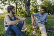 Due amici multiculturali seduti nel parco con dispositivo mobile e documenti — Foto stock