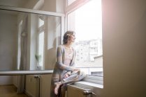 Mature woman looking out of window — Stock Photo