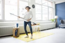Mujer vital en casa usando gafas VR y limpiando el piso - foto de stock