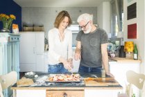 Coppia matura che prepara una pizza in cucina a casa — Foto stock