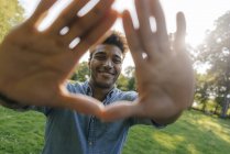 Портрет усміхнений молодий афроамериканець чоловік робить палець кадру в парку — стокове фото