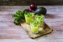 Glasses of avocado cream with chili flakes, cress and parsley — Stock Photo