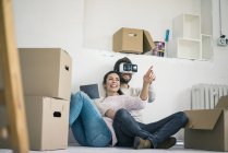 Пара сидящих в новом доме с мужчиной в VR очках — стоковое фото