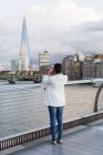 UK, London, woman standing on a bridge taking picture of The Shard — Stock Photo