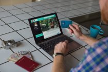Hombre usando la tarjeta de crédito y el ordenador portátil en casa - foto de stock