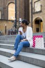 Reino Unido, Londres, mulher com sacos de compras e telefone celular sentado nas escadas da cidade — Fotografia de Stock
