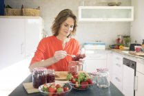 Portrait de femme faisant de la confiture de fraises dans la cuisine à la maison — Photo de stock