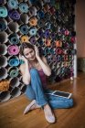 Mujer madura relajada escuchando música frente a una variedad de colchonetas de yoga - foto de stock