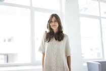 Portrait of smiling woman standing in bright room near window — Stock Photo