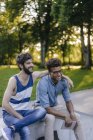 Dos felices amigos multiculturales sentados en el skatepark - foto de stock