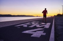 Portogallo, Lisbona, jogger che corre vicino al fiume Tago al tramonto — Foto stock