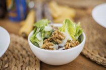 Romaine lettuce with walnuts in bowl — Stock Photo