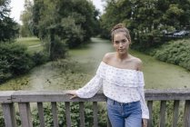 Retrato de una joven de pie sobre un puente - foto de stock
