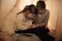 Duas meninas com telefone celular e tablet no quarto das crianças — Fotografia de Stock