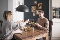 Couple eating salad at dining table at home — Stock Photo