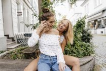 Due giovani donne felici con il cellulare in città — Foto stock