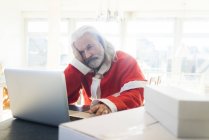 Père Noël frustré en utilisant un ordinateur portable à la maison — Photo de stock