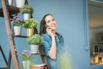 Beautiful woman in her home, decorated with plants, talking on the phone — Stock Photo