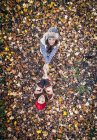 Due donne felici in piedi in foglie autunnali e si tengono per mano — Foto stock