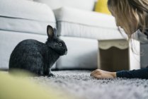 Mädchen mit Kaninchen im Wohnzimmer — Stockfoto