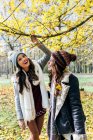 Two pretty women having fun in an autumnal forest — Stock Photo