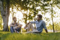 Zwei multikulturelle Freunde sitzen mit Handy und Papieren im Park — Stockfoto