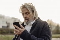 Grave uomo anziano che tiene il cellulare all'aperto — Foto stock