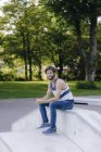 Homme avec téléphone portable assis dans skatepark — Photo de stock