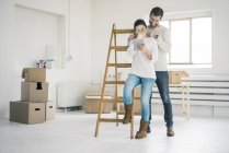 Couple riant à l'échelle dans la nouvelle maison en regardant la tablette — Photo de stock