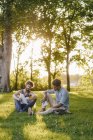 Two multiethnic friends sitting in park with mobile device and papers — Stock Photo