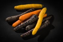 Свіжа апельсин і фіолетовий морква на чорному фоні — стокове фото