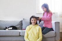 Ragazzina treccia i capelli della sorella — Foto stock