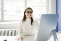 Smiling businesswoman working at desk in office — Stock Photo