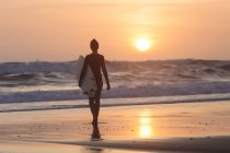 Індонезія, Балі, молода жінка з дошки для серфінгу на заході сонця — стокове фото