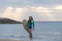 Indonesia, Bali, giovane donna con tavola da surf che cammina in spiaggia — Foto stock