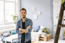 Portrait of smiling man standing with crossed arms at home — Stock Photo