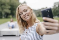 Portrait of smiling young woman taking selfie in skate park — Stock Photo