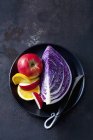 Frisches Stück lila Kohl mit Apfel und Orange auf Teller auf dunklem Grunge-Hintergrund — Stockfoto