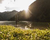 Austria, Tirolo, escursionista in posa yoga rinfrescante nel lago di montagna — Foto stock