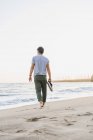 Back view of man walking barefoot on the beach — Stock Photo