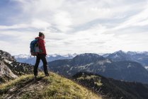 Austria, Tirolo, giovane donna in piedi nel paesaggio montano e guardando la vista — Foto stock