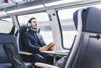 Empresário relaxante ouvir música no trem — Fotografia de Stock