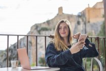Spanien, alquezar, Porträt einer entspannten jungen Frau mit Laptop und Handy, die auf der Terrasse sitzt — Stockfoto