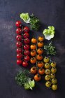 Tomates cherry frescos y coloridos y hojas de ensalada sobre fondo grunge oscuro - foto de stock